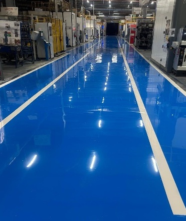 Blaue Epoxidharz-Fahrspur mit weißen Linienmarkierungen zwischen Maschinen