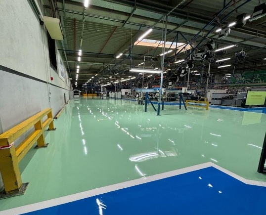 Produktionshalle mit hellgrün beschichtetem Epoxidharzboden und blau markierter Zone
