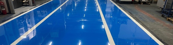 Fertig gestellte blaue Epoxidharz-Fahrspur mit weißen Linien, Blick in die Halle